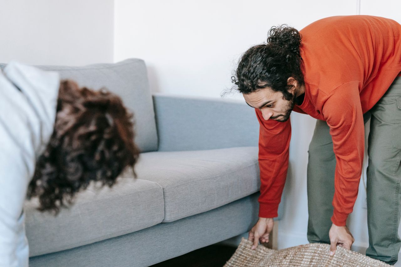 Un couple range son salon, en organisant les meubles et les tapis avec esprit d’équipe.